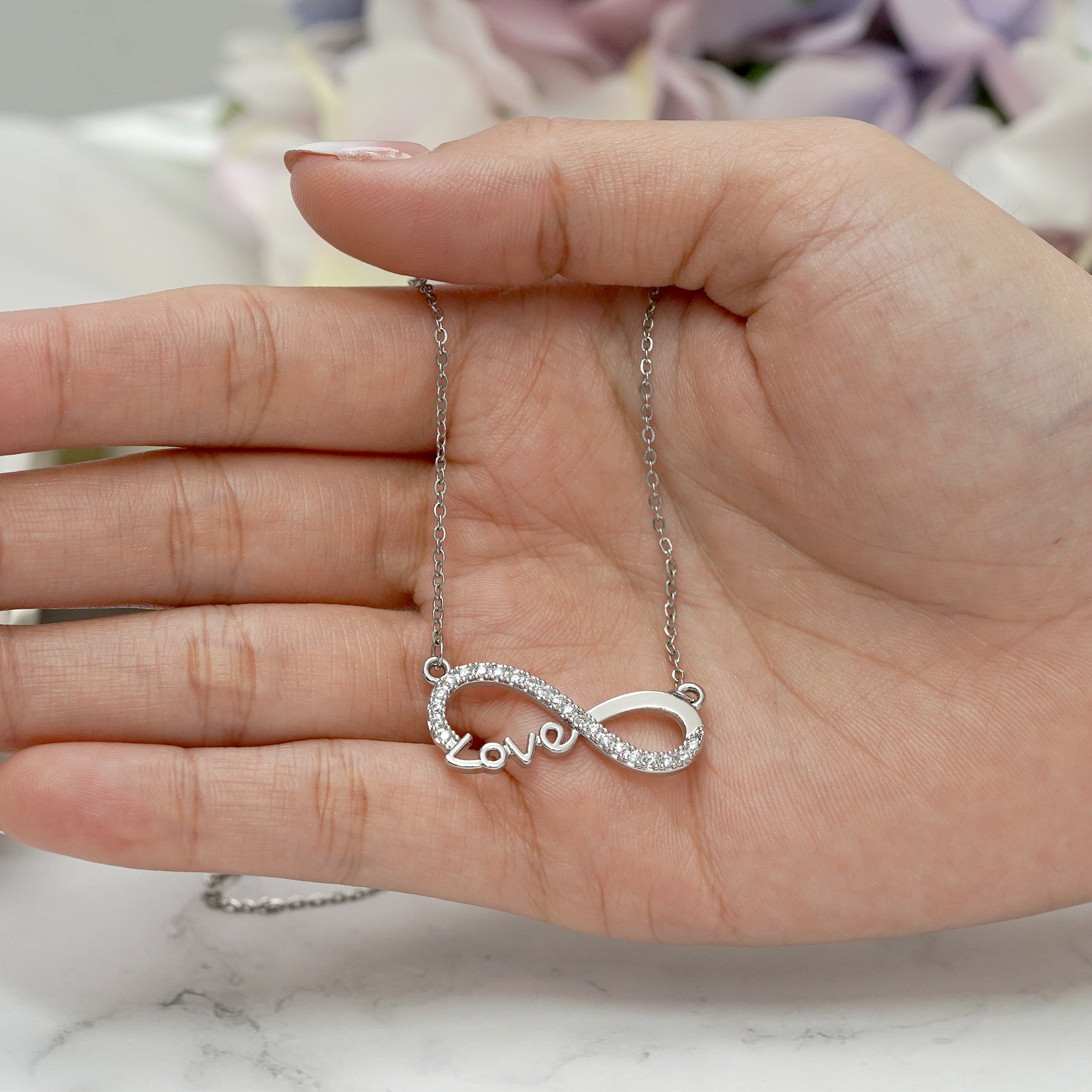 Infinity Love pendant necklace with pavé stones on a silver chain.