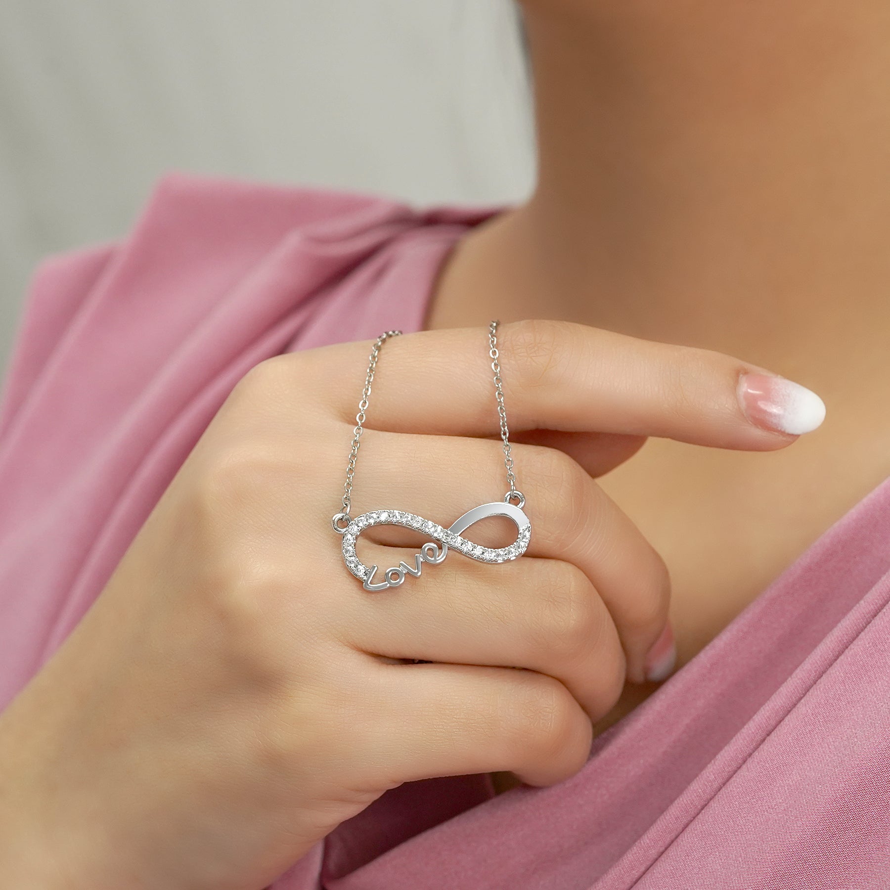 Infinity Love pendant necklace with a rhinestone-encrusted loop and Love script on a silver chain.