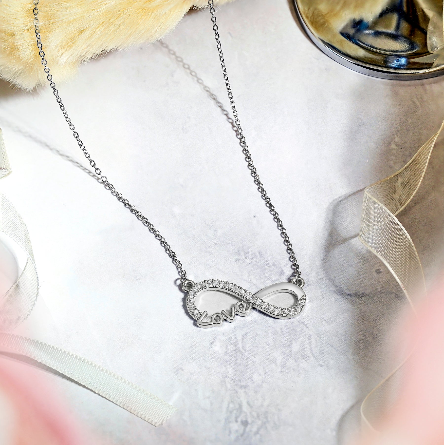 Infinity Love Pendant Necklace in 18K white gold plating with sparkling stones on a delicate chain.