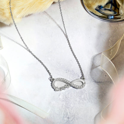 Infinity Love Pendant Necklace in 18K white gold plating with sparkling stones on a delicate chain.